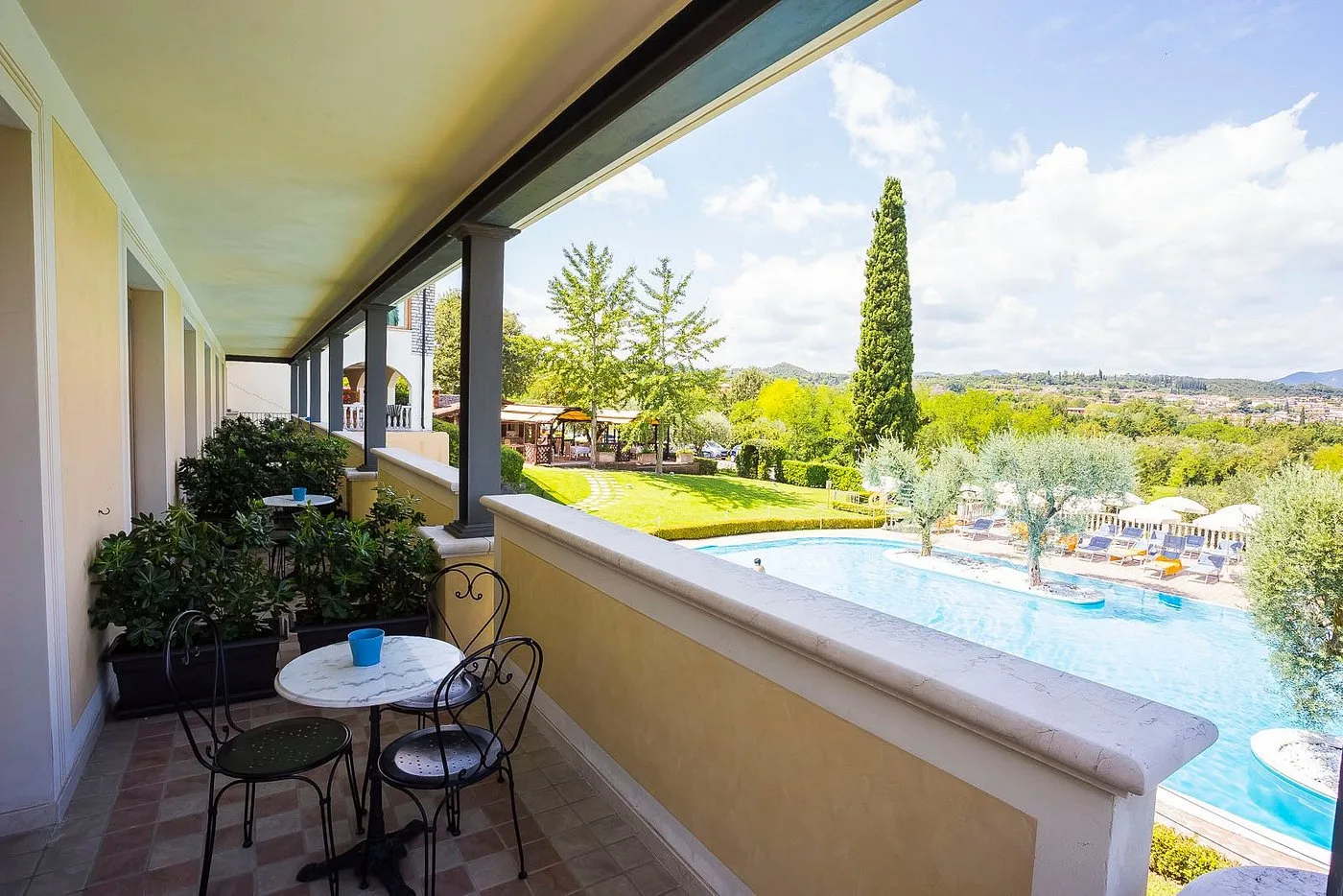 Balcone con tavolino e sedie affacciato sulla piscina e il giardino