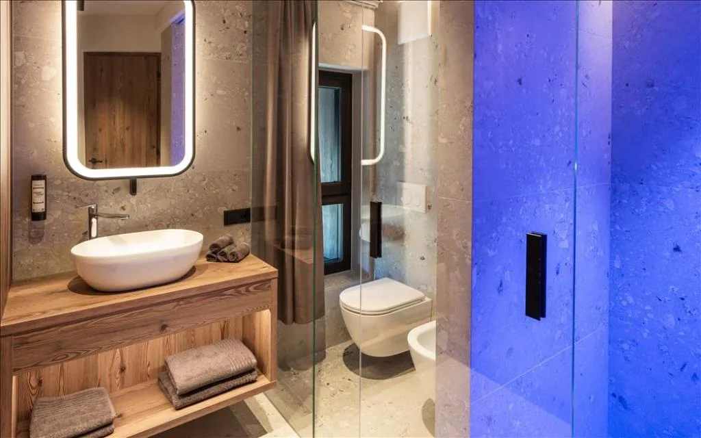 Bagno con lavabo in legno, doccia in vetro e illuminazione blu decorativa
