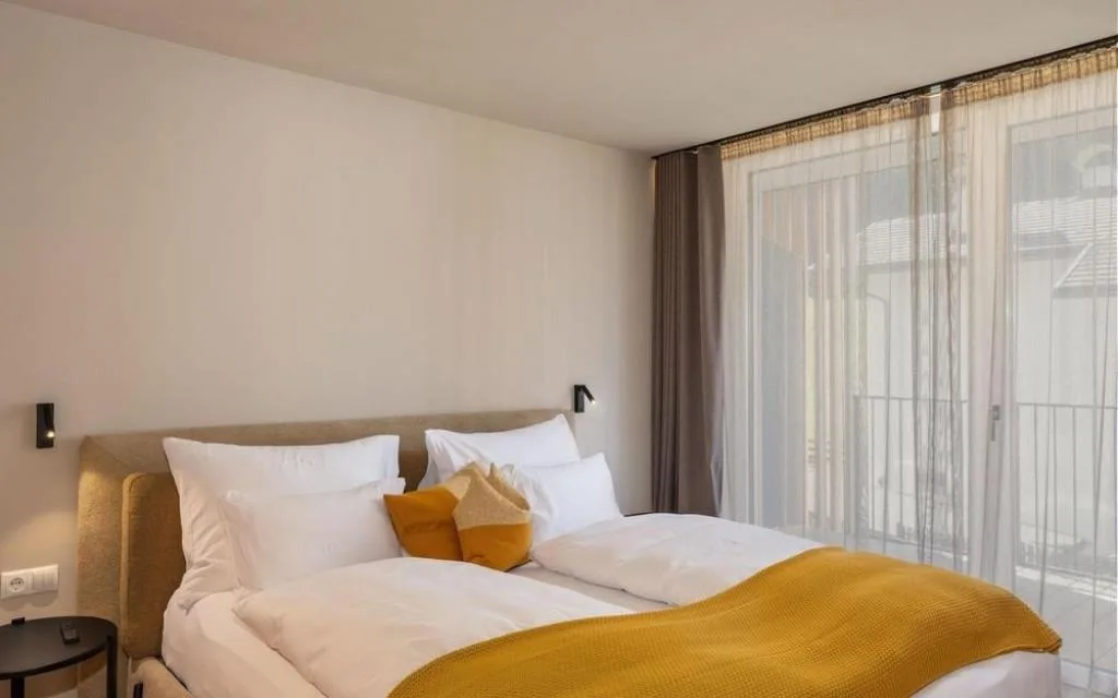 Camera da letto luminosa con letto matrimoniale e ampia vetrata