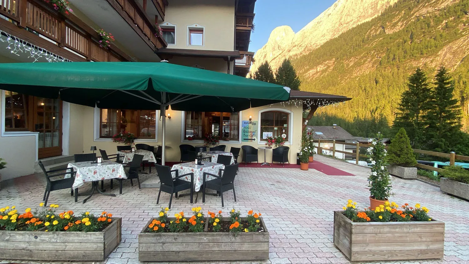 Terrazza esterna con ombrellone verde e fioriere con vista sulle montagne al tramonto