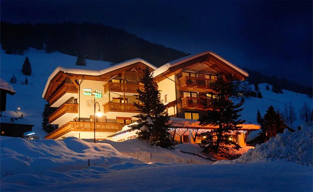 Hotel illuminato di notte nella neve con abete decorato