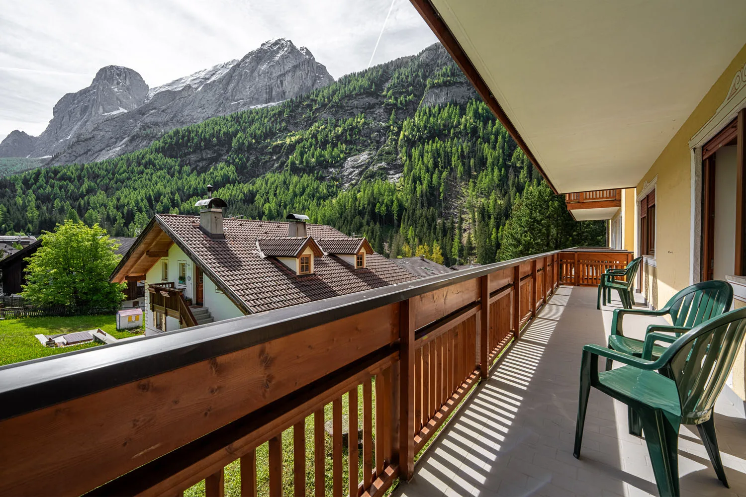 Ampio balcone con sedie e vista sulle Dolomiti e i tetti del villaggio