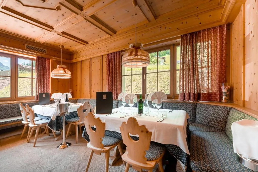 Ristorante con pareti in legno, tavoli apparecchiati e vista sui prati