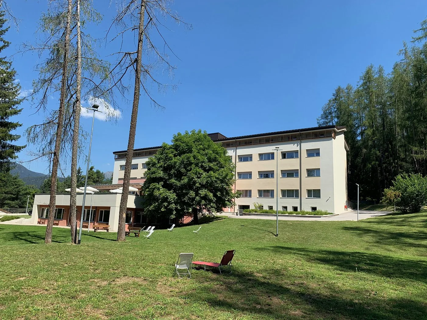 Facciata dell'hotel con ampio prato verde e sedie a sdraio in estate