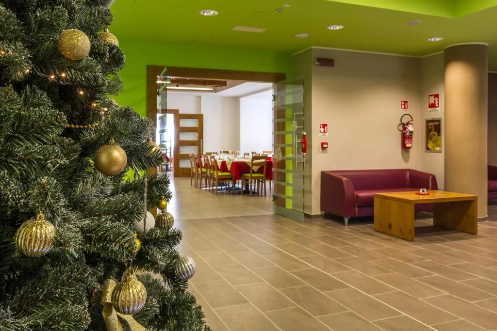 Hall dell'hotel con albero di Natale decorato e sala ristorante sullo sfondo