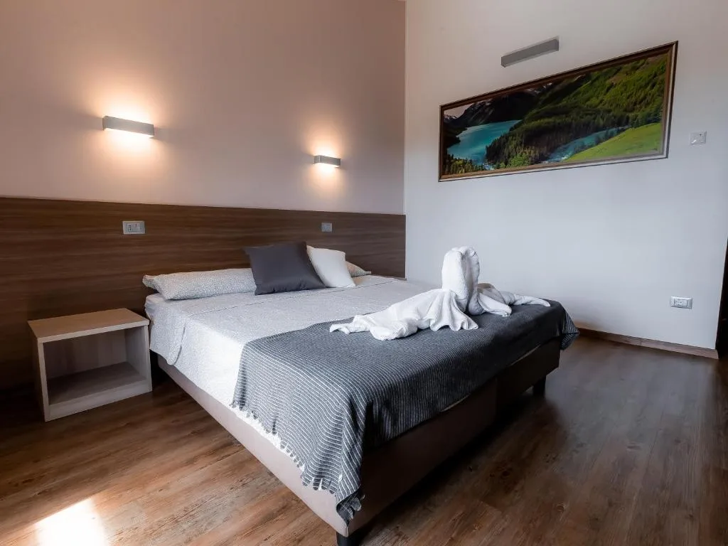 Camera matrimoniale con parquet e quadro di paesaggio alpino sopra il letto
