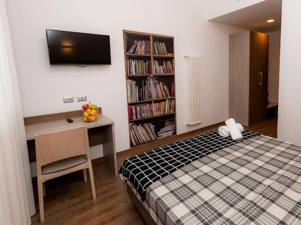Camera con letto, scrivania, TV a parete e libreria colorata