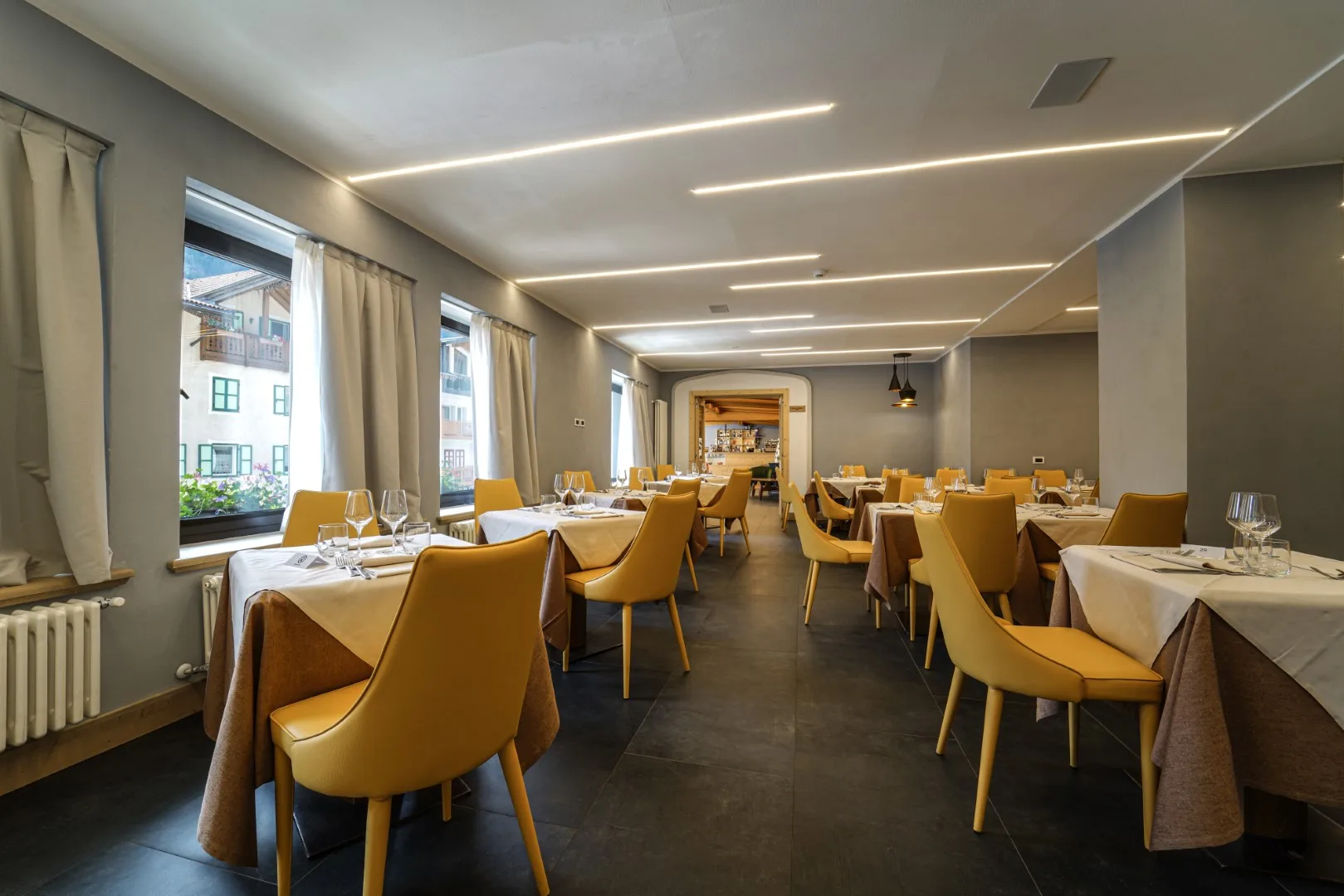 Sala ristorante moderna con sedie gialle e vetrate affacciate sul paese