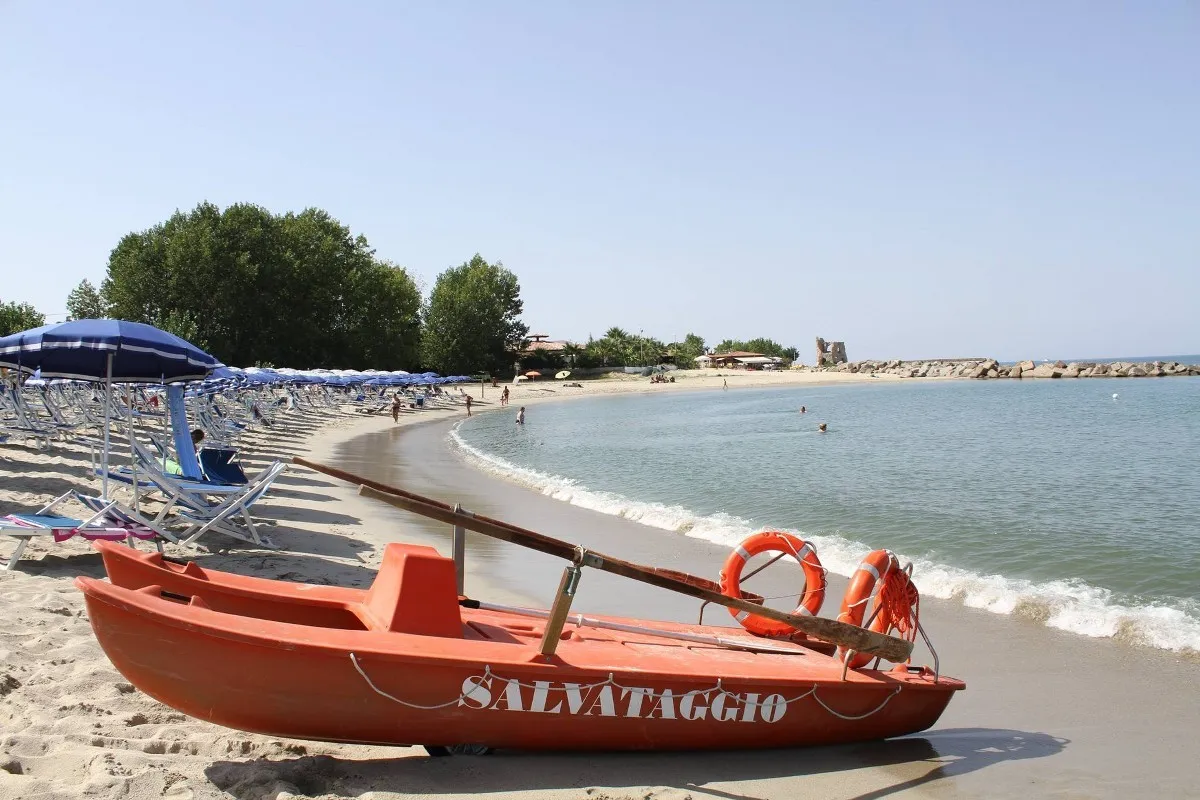 Barca di salvataggio arancione sulla spiaggia con ombrelloni e mare