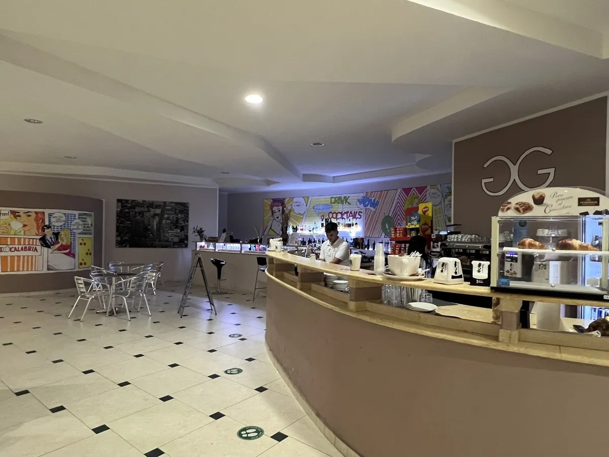 Bar interno con bancone curvo, tavolini e decorazioni pop art