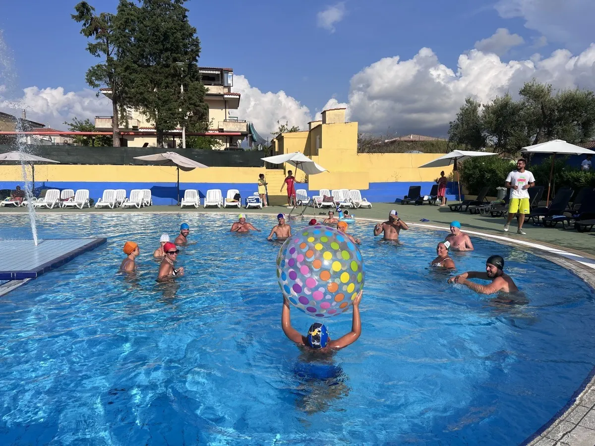 Attività di acquagym in piscina con animatore e partecipanti