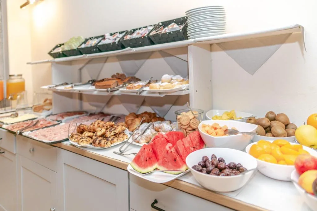Ricco buffet della colazione con frutta fresca, dolci, cornetti e salumi