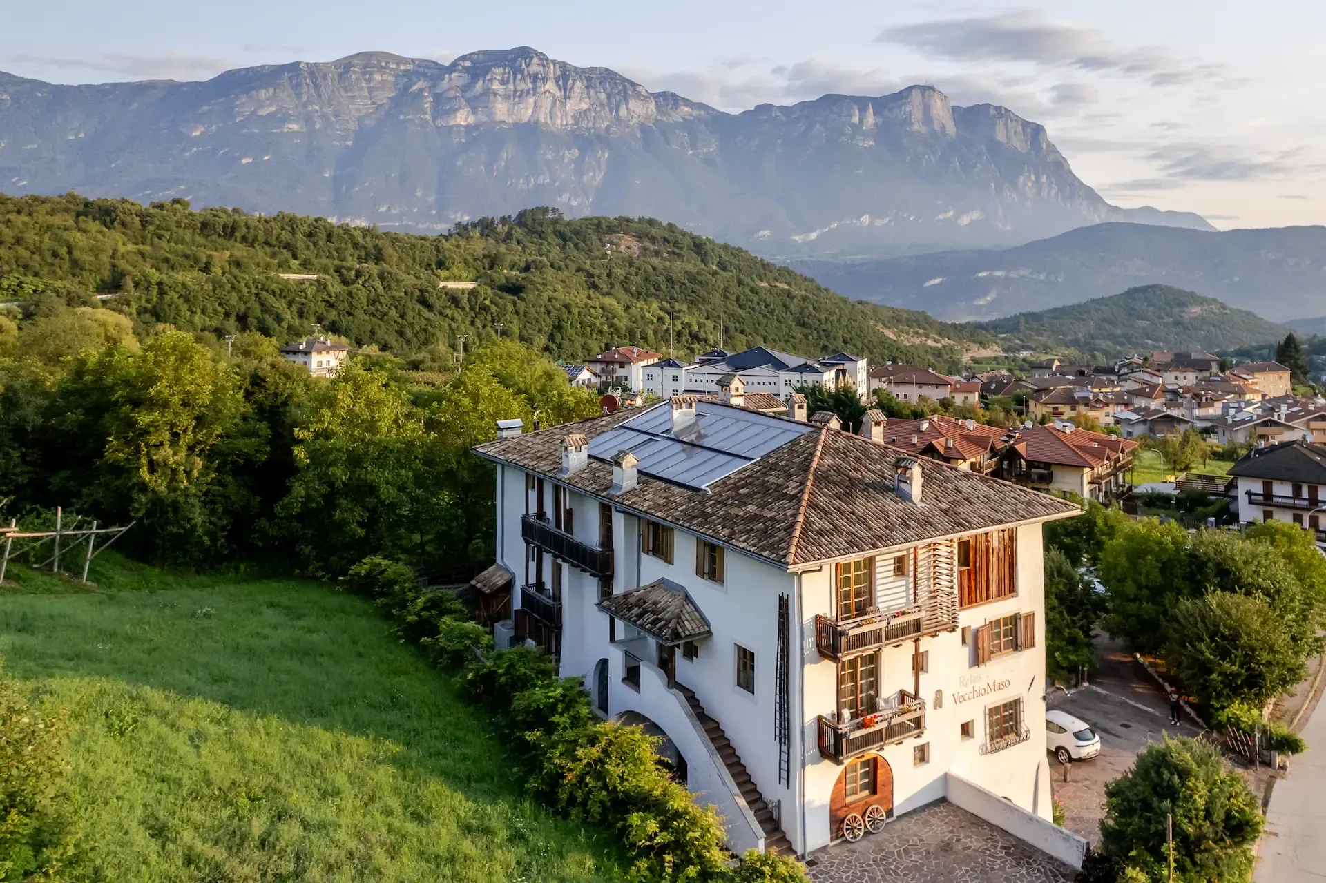 Veduta aerea dell'hotel immerso nel verde con pannelli solari sul tetto e vista sulle Dolomiti