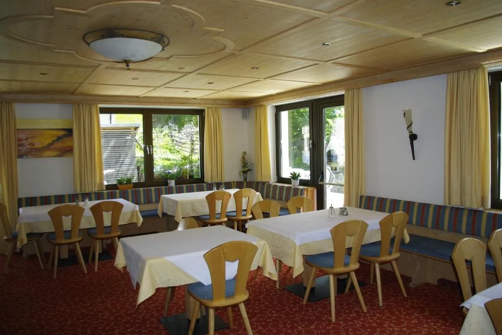Sala ristorante con tavoli apparecchiati, sedie in legno e soffitto decorato, affacciata sul giardino