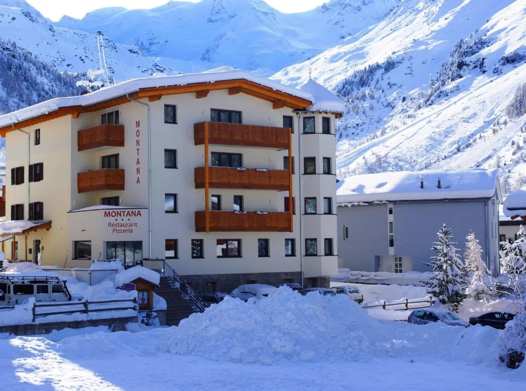 Hotel Montana in inverno con cumuli di neve e montagne innevate sullo sfondo