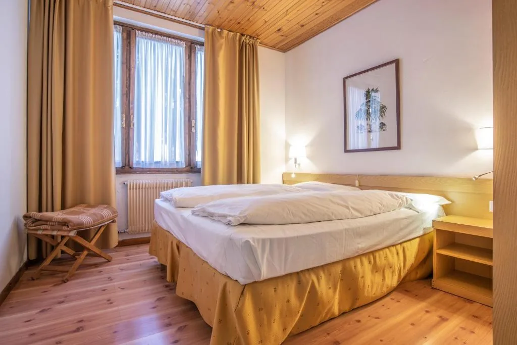 Camera con letto matrimoniale, soffitto in legno e tende gialle