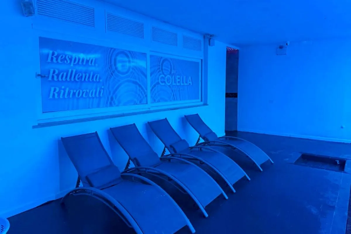 Area relax della spa con lettini e insegna Colella illuminata di blu