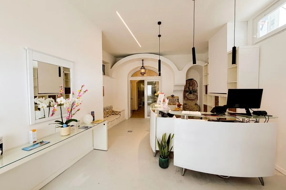 Reception della spa con bancone bianco, specchio e fiori decorativi