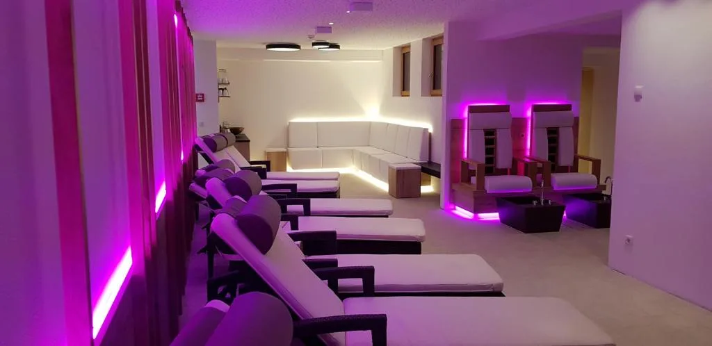 Zona relax della spa con lettini imbottiti e illuminazione LED rosa e viola