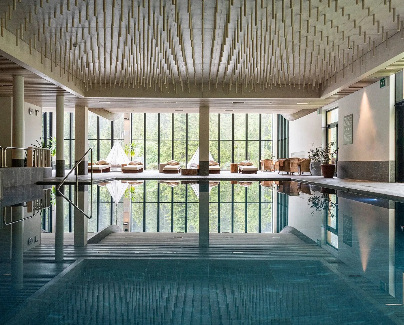 Piscina interna coperta con grandi vetrate affacciate sul bosco e lettini