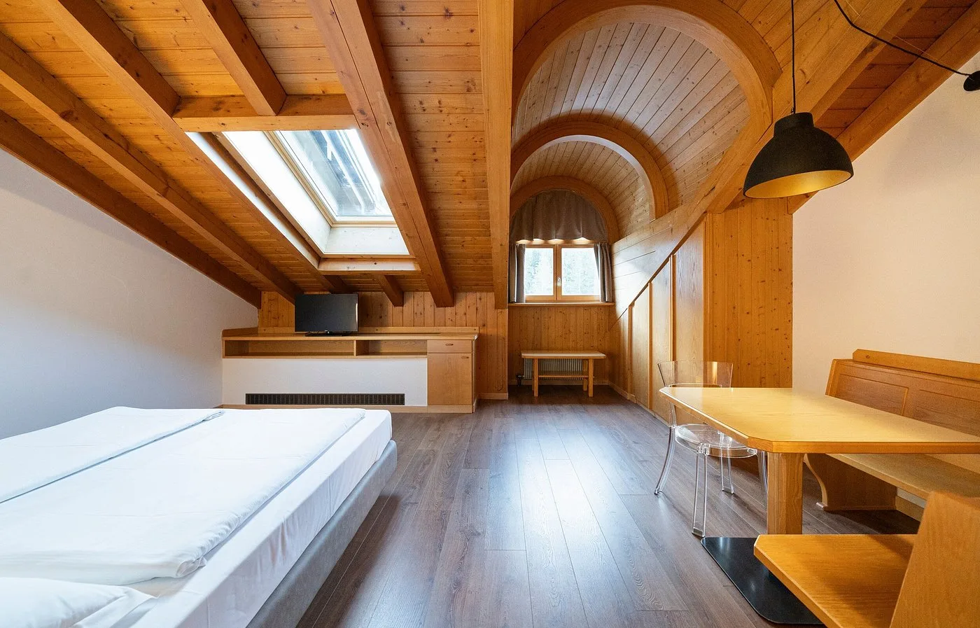 Camera mansardata con soffitto in legno a volta, letto matrimoniale e tavolo