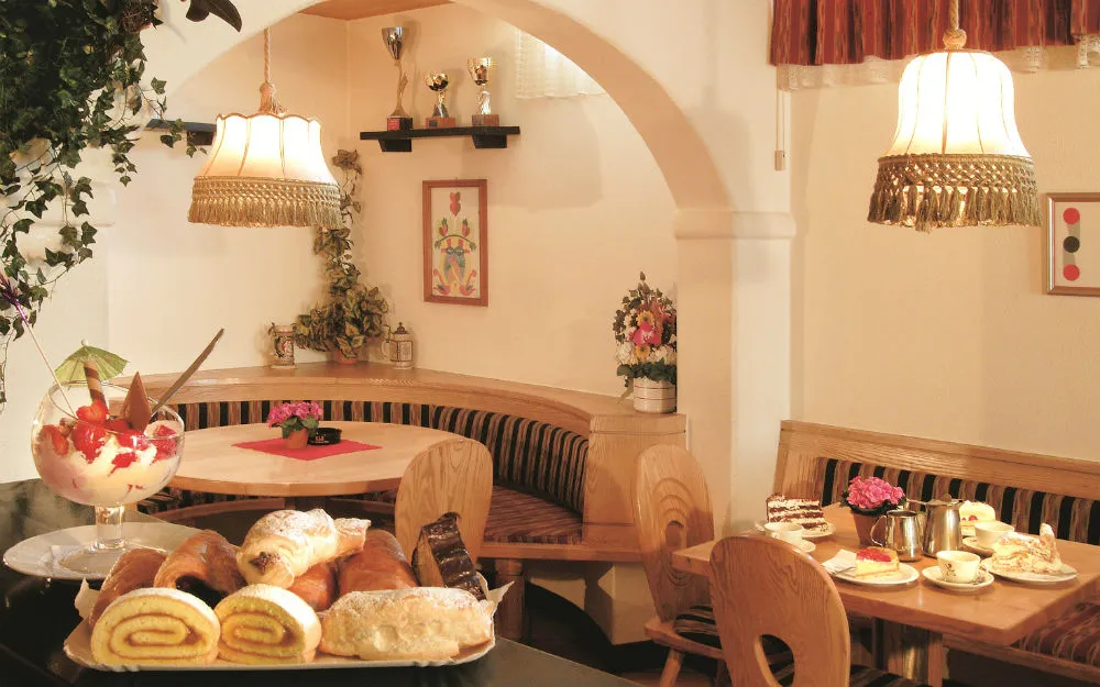 Sala colazione con dolci, cornetti e coppe di gelato su tavoli in legno