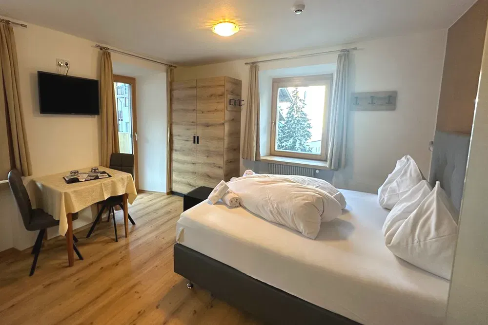 Camera da letto moderna con letto matrimoniale, TV a parete e pavimento in legno