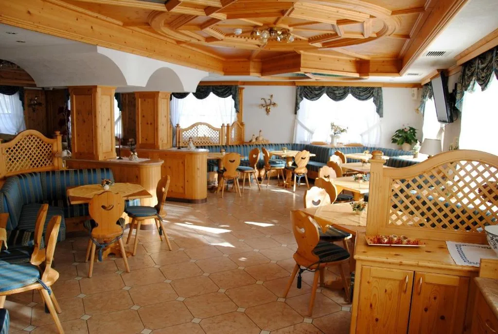Sala ristorante con arredi in legno chiaro e sedute in stile alpino