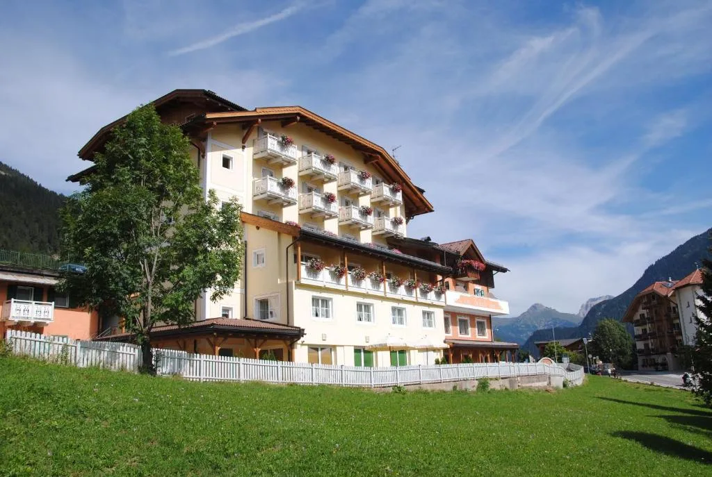 Vista esterna dell'hotel con balconi fioriti e montagne circostanti