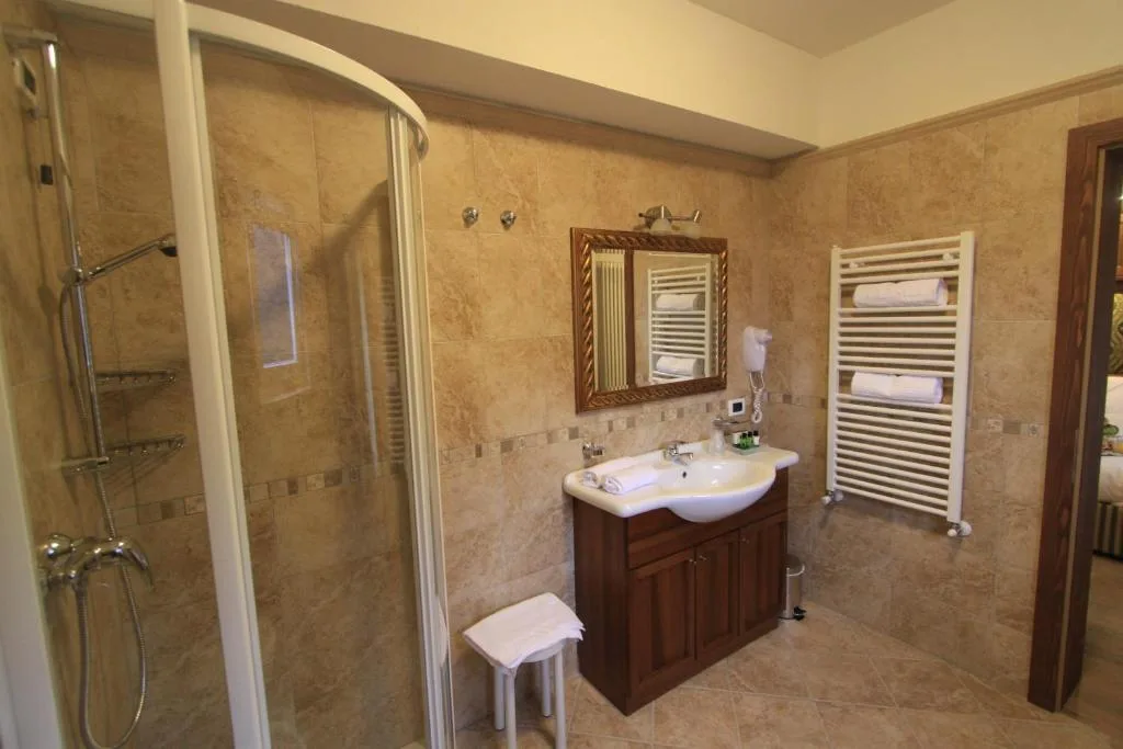 Bagno con doccia, lavabo, specchio e scaldasalviette