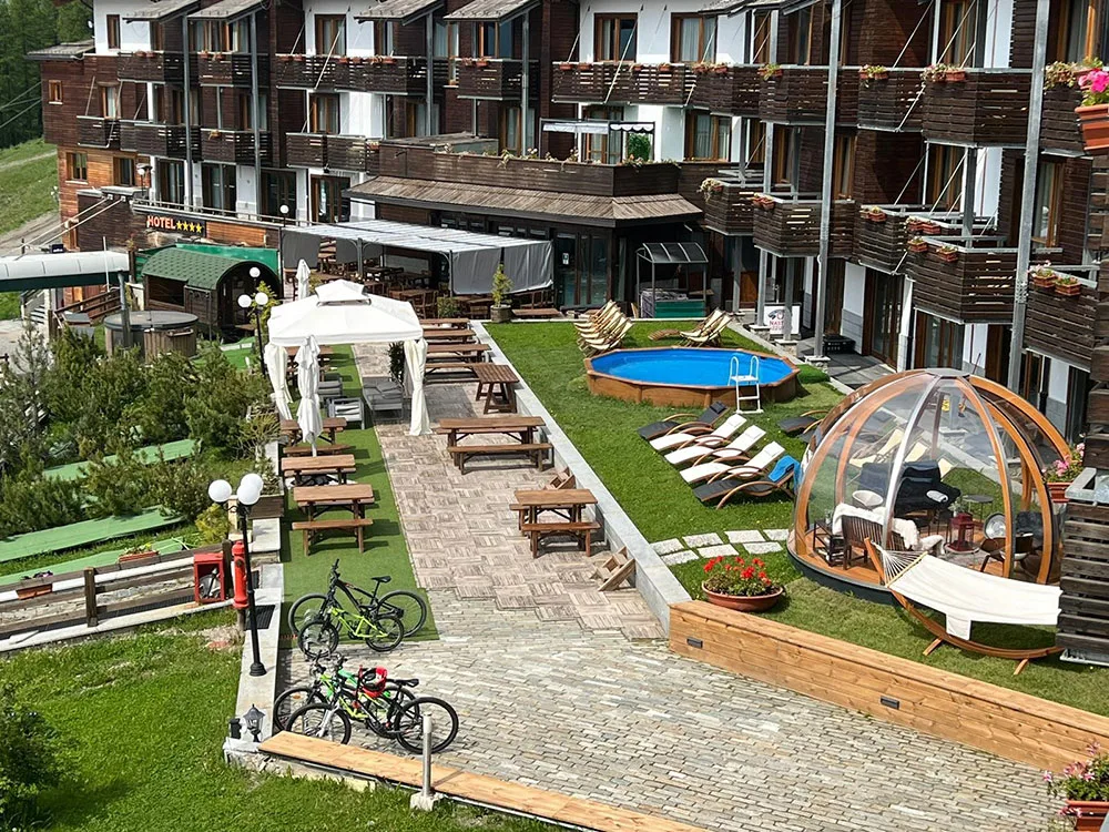 Cortile dell'hotel con piscina esterna, gazebo, cupola relax e biciclette in estate
