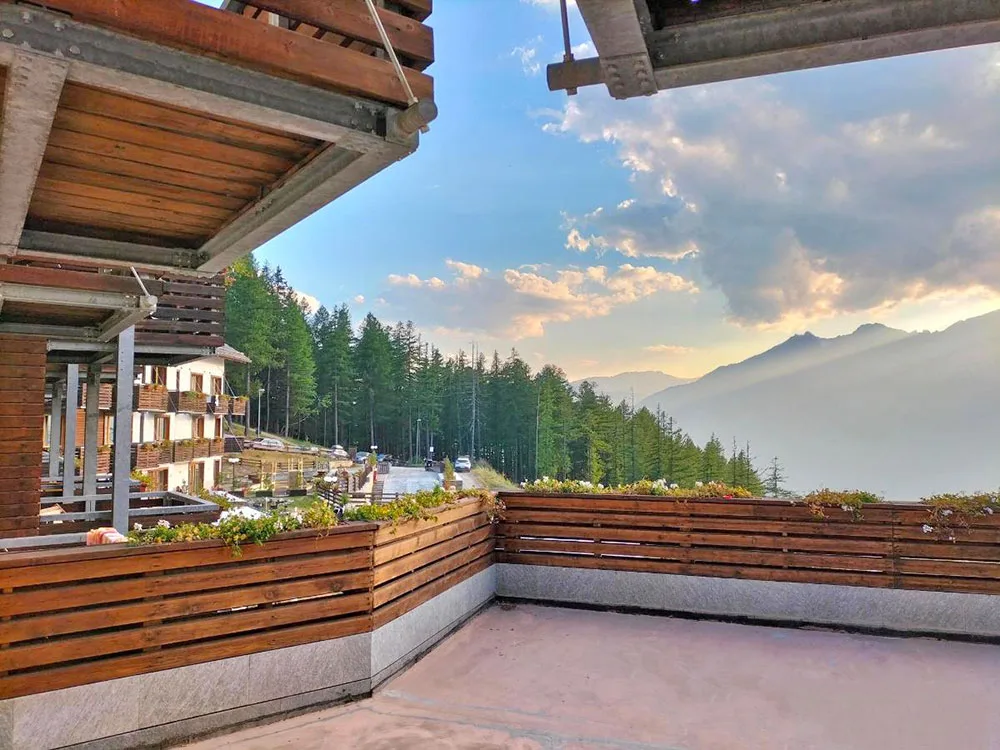 Terrazza privata in legno con vista sulle montagne e bosco al tramonto