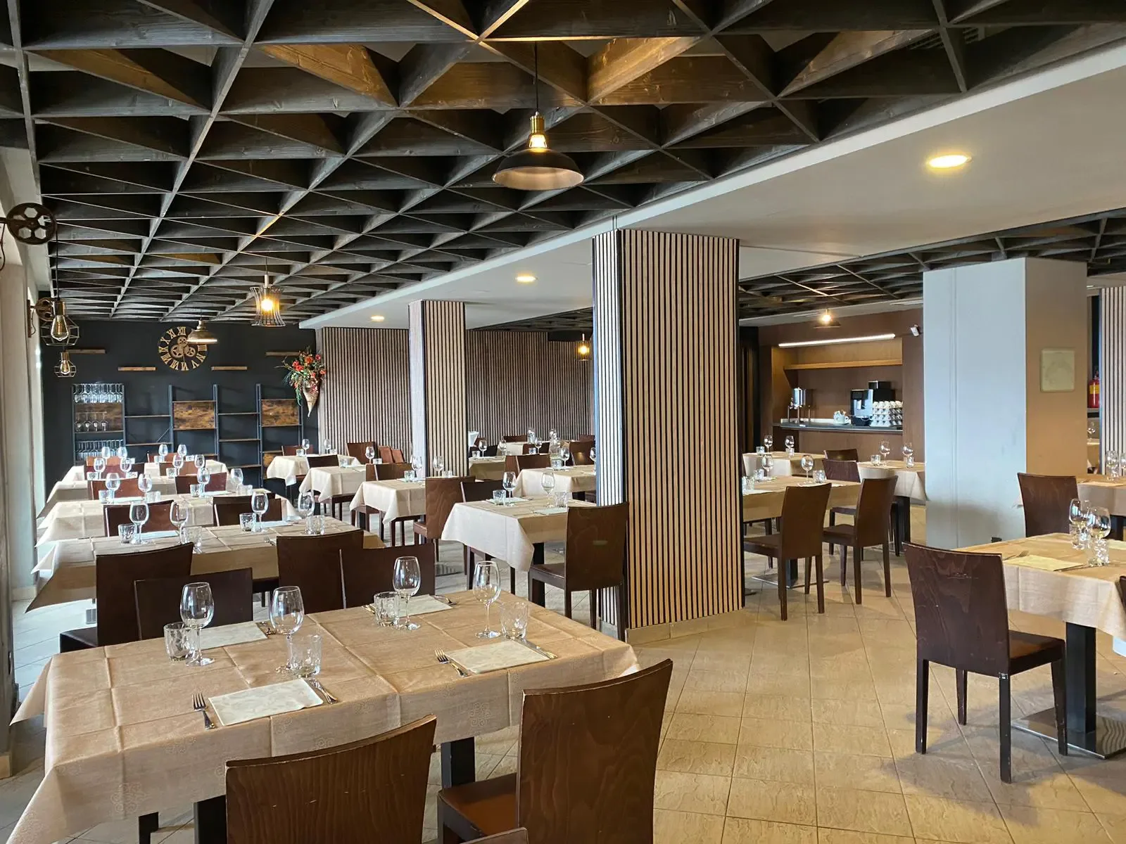 Sala ristorante elegante con soffitto a travi in legno e tavoli apparecchiati