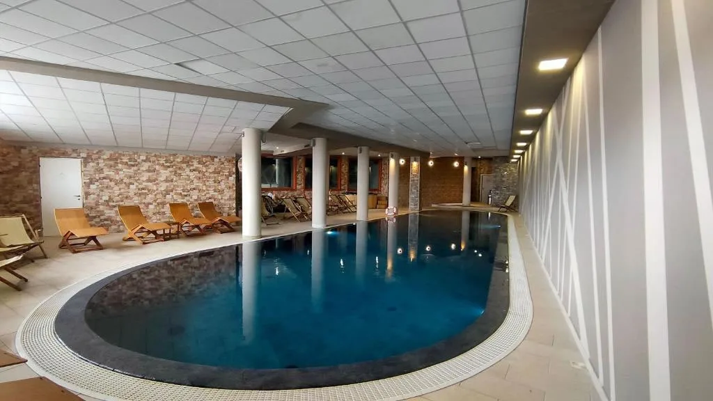 Piscina coperta interna con lettini prendisole e pareti in pietra