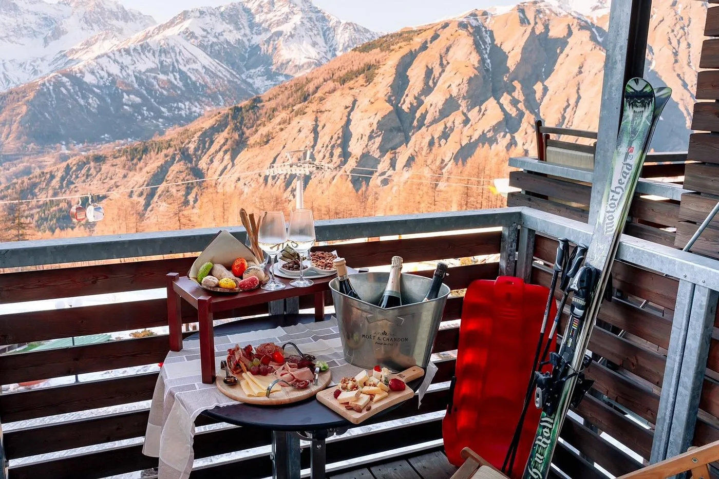 Balcone con aperitivo, tagliere e champagne affacciato sulle montagne e impianto di risalita