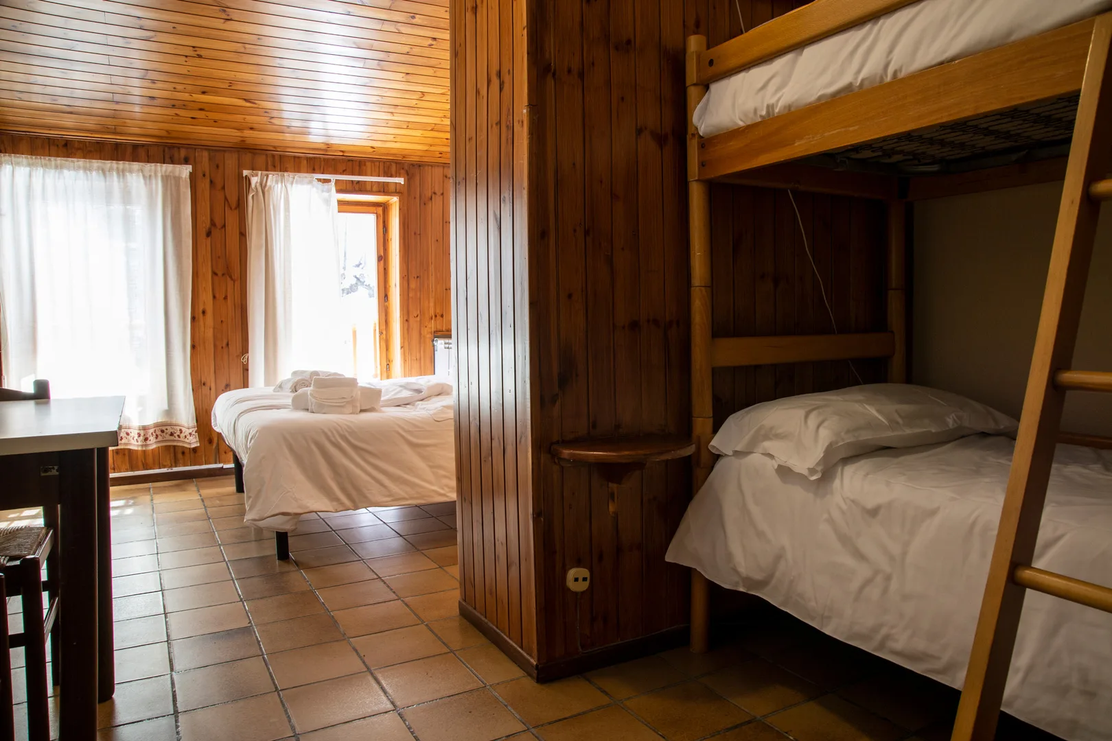 Camera in legno con letto matrimoniale e letto a castello vicino alla finestra