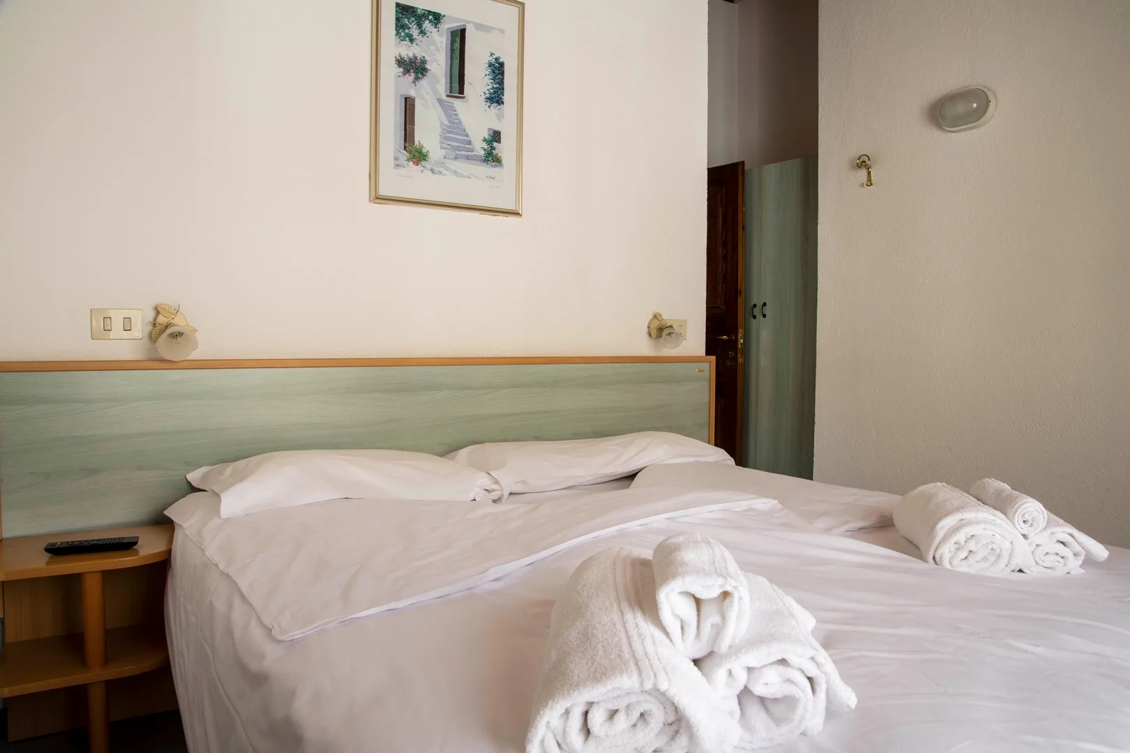 Camera con letto matrimoniale, testata verde e quadro decorativo alla parete