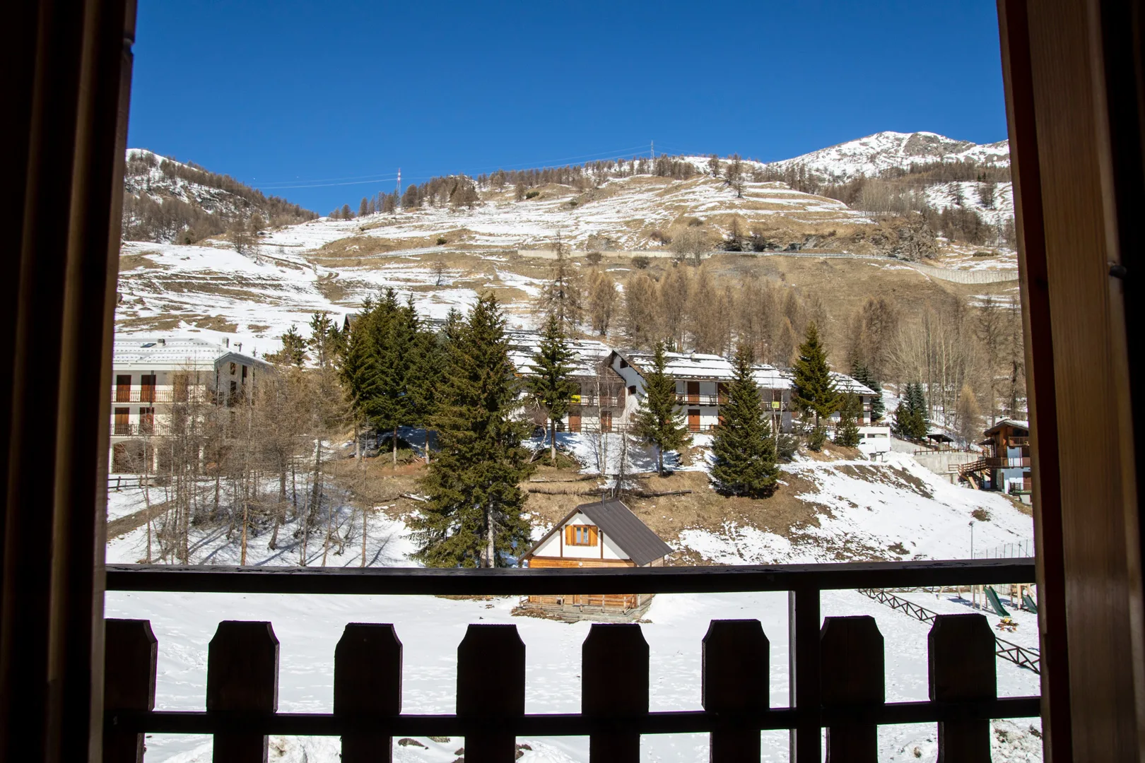 Vista dalla finestra su chalet in legno e montagne innevate con alberi