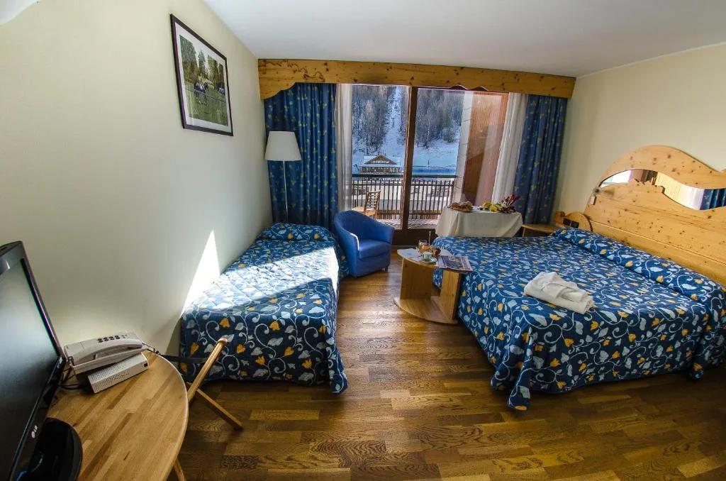 Camera tripla con arredi in legno e vista sulle piste innevate