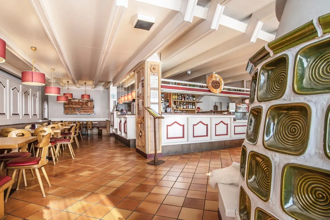 Interno del bar ristorante con bancone bianco e rosso e tavoli in legno