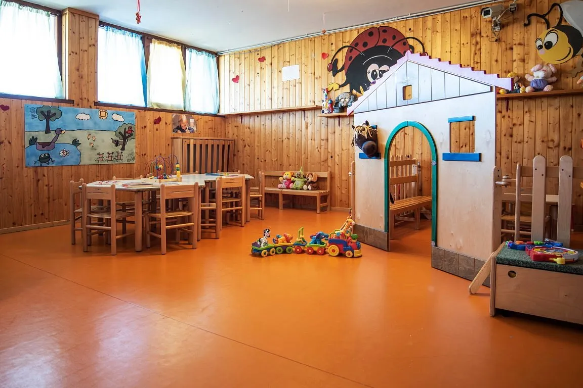 Sala giochi per bambini con tavolo, sedie in legno e casetta gioco