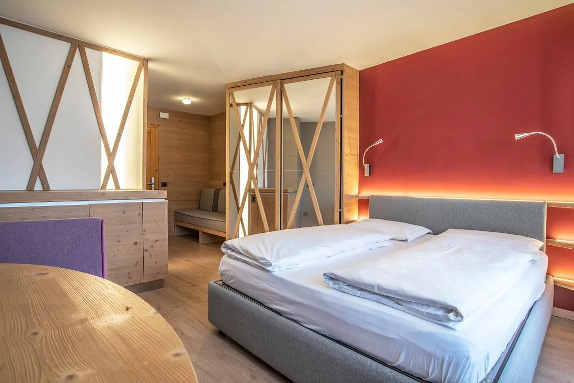 Camera con letto matrimoniale, parete rossa e dettagli in legno