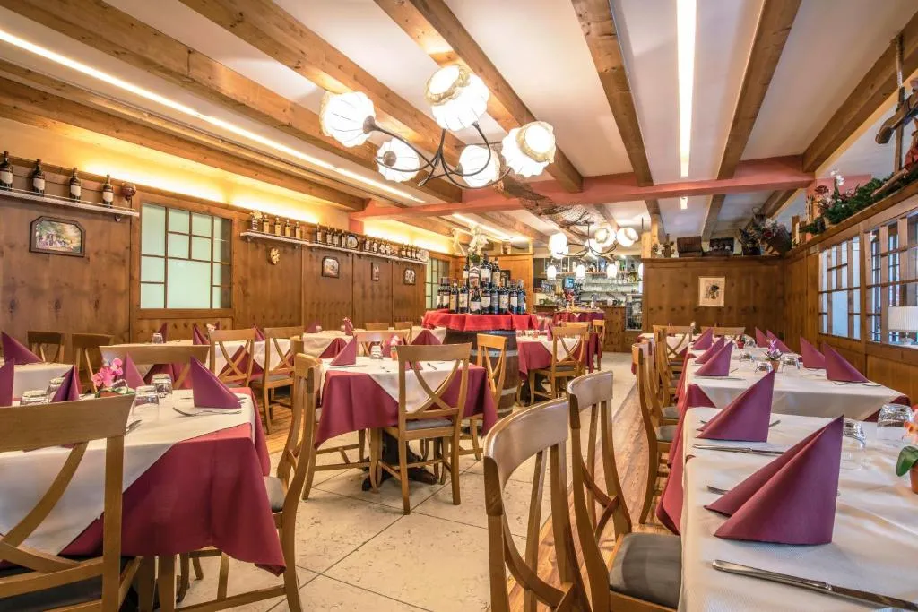 Sala ristorante rustica con tavoli, tovaglioli rossi e pareti in legno