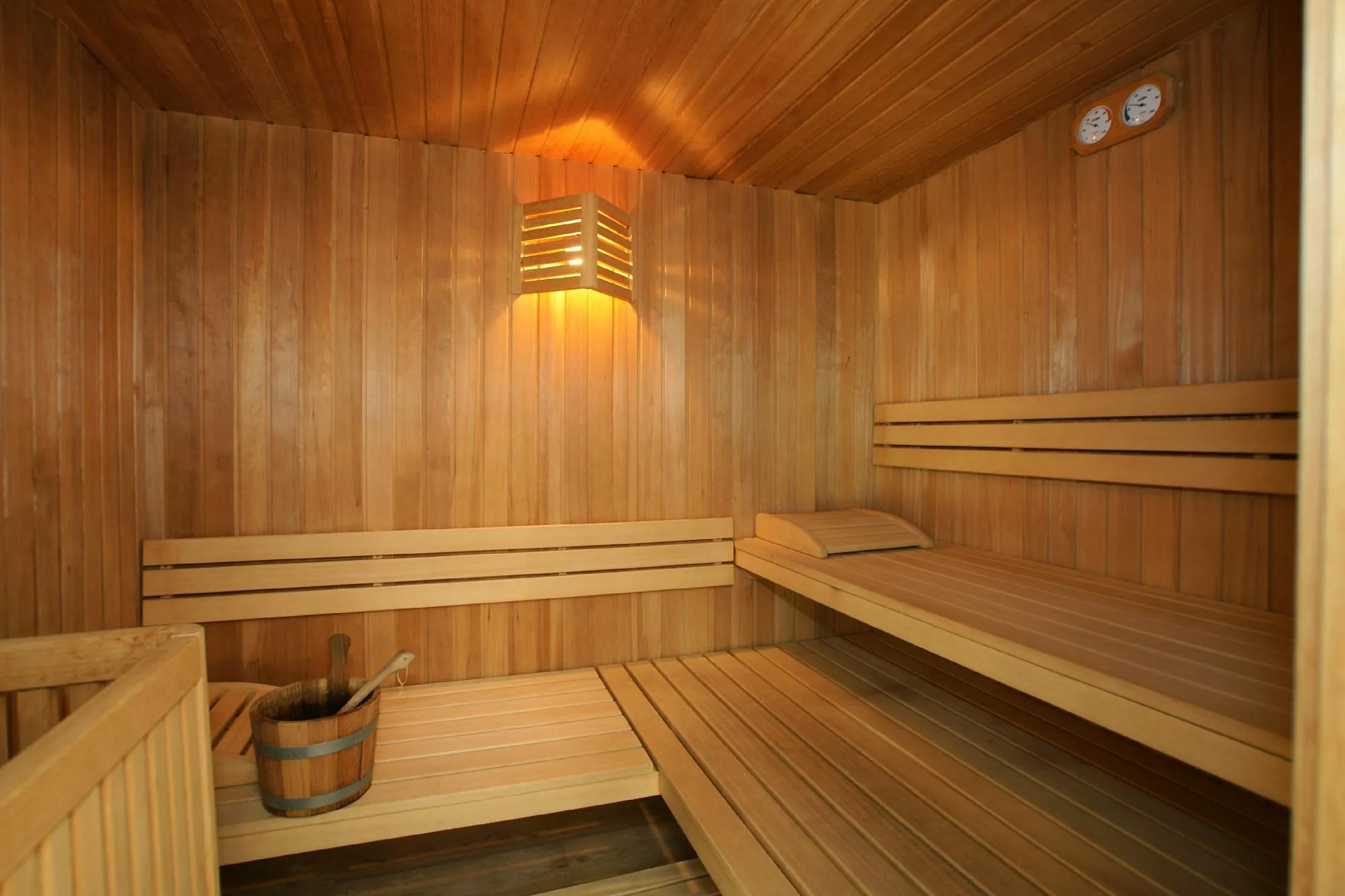 Sauna finlandese in legno con panche e secchiello tradizionale