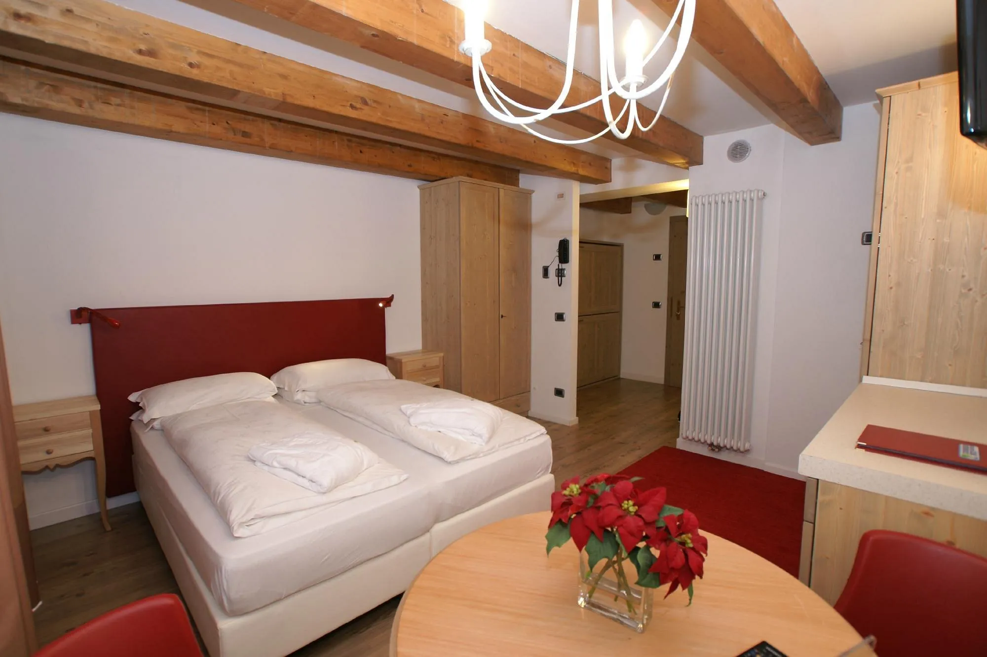 Camera spaziosa con letto matrimoniale, tavolo rotondo e travi a vista