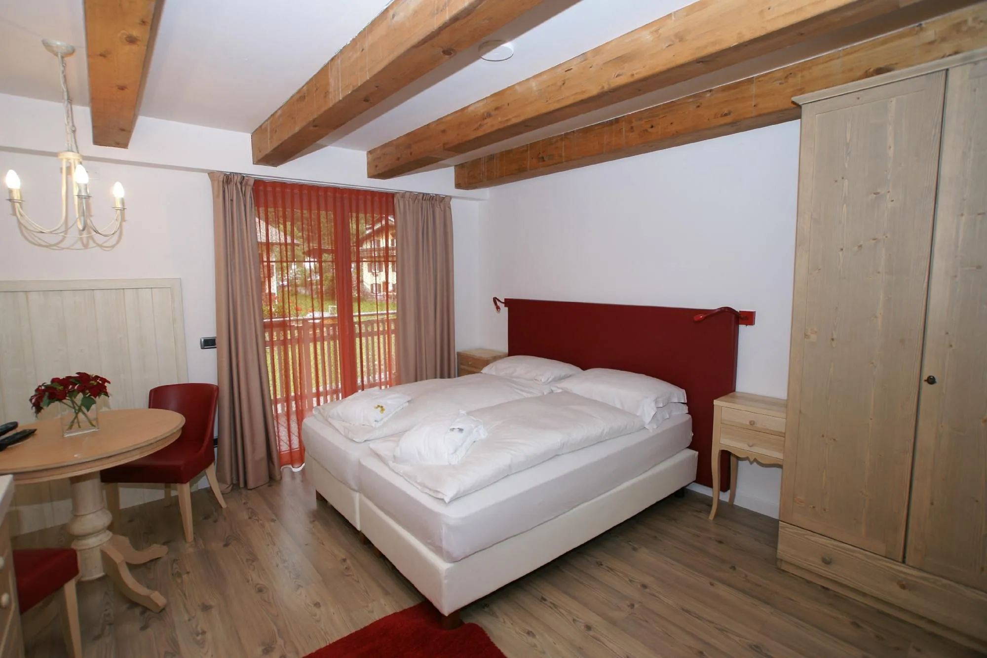 Camera con letto matrimoniale, tavolino e balcone affacciato sul paese