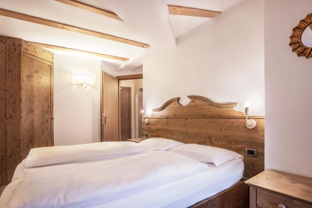 Camera da letto con testiera in legno intagliato e travi a vista