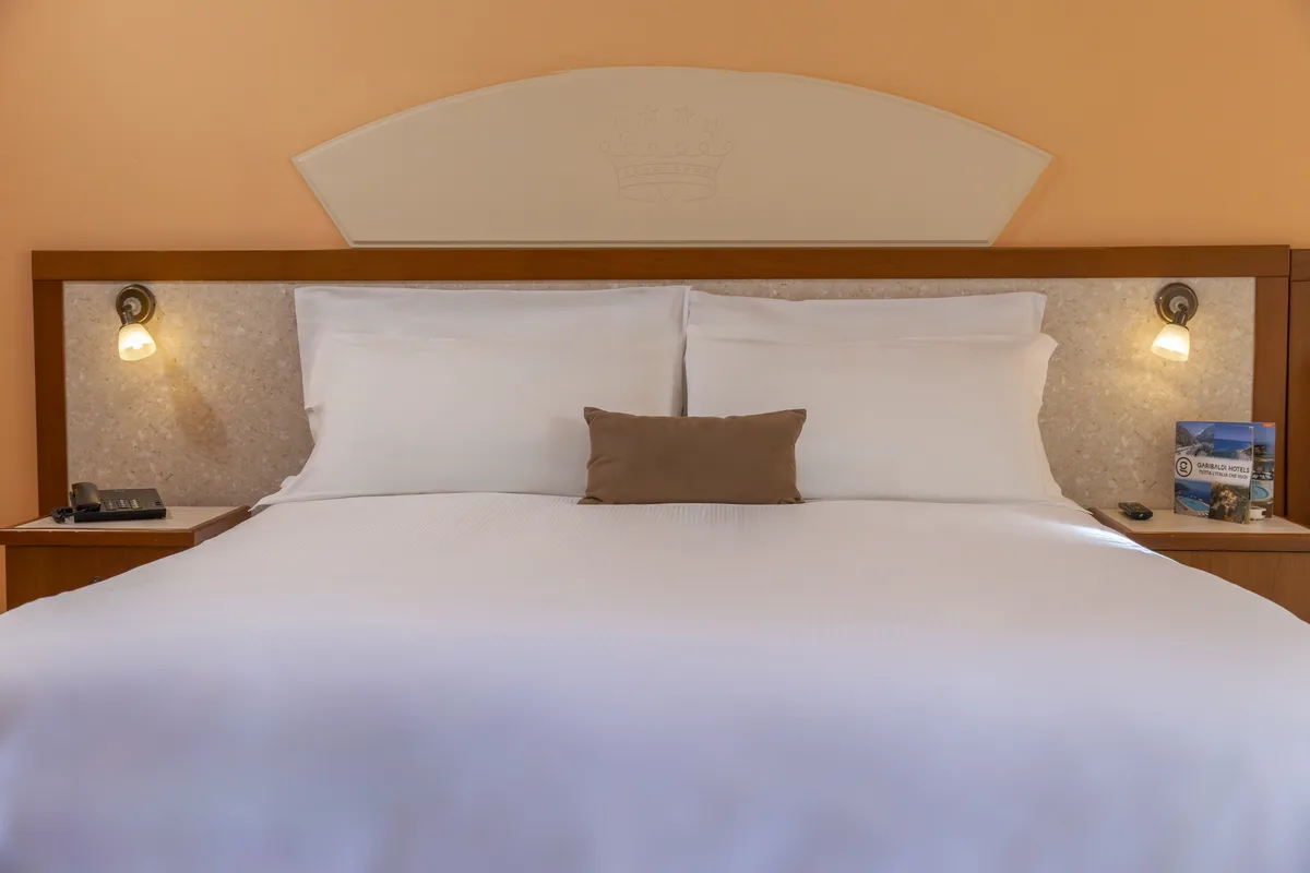 Letto matrimoniale con testiera in legno e biancheria bianca
