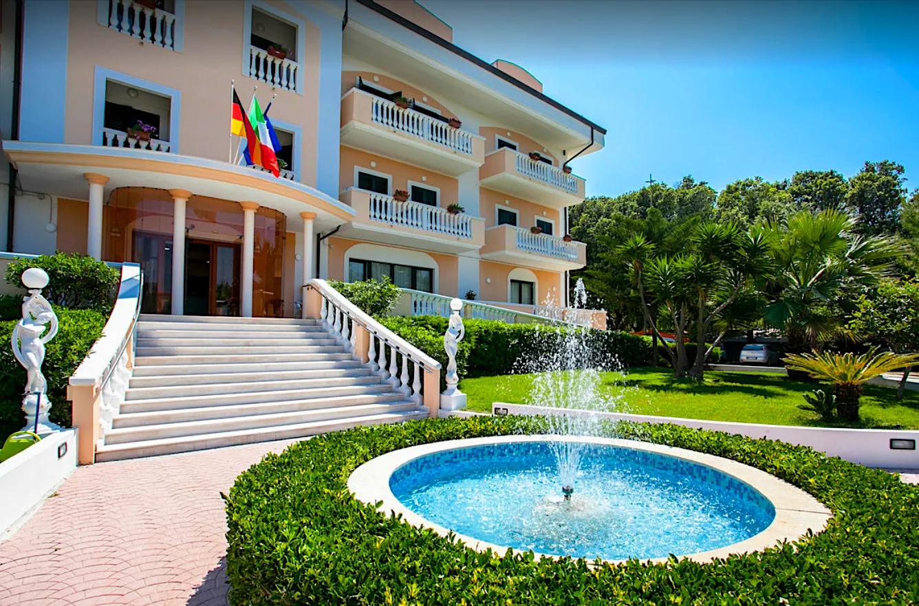 Facciata dell'hotel con scalinata, fontana e giardino curato