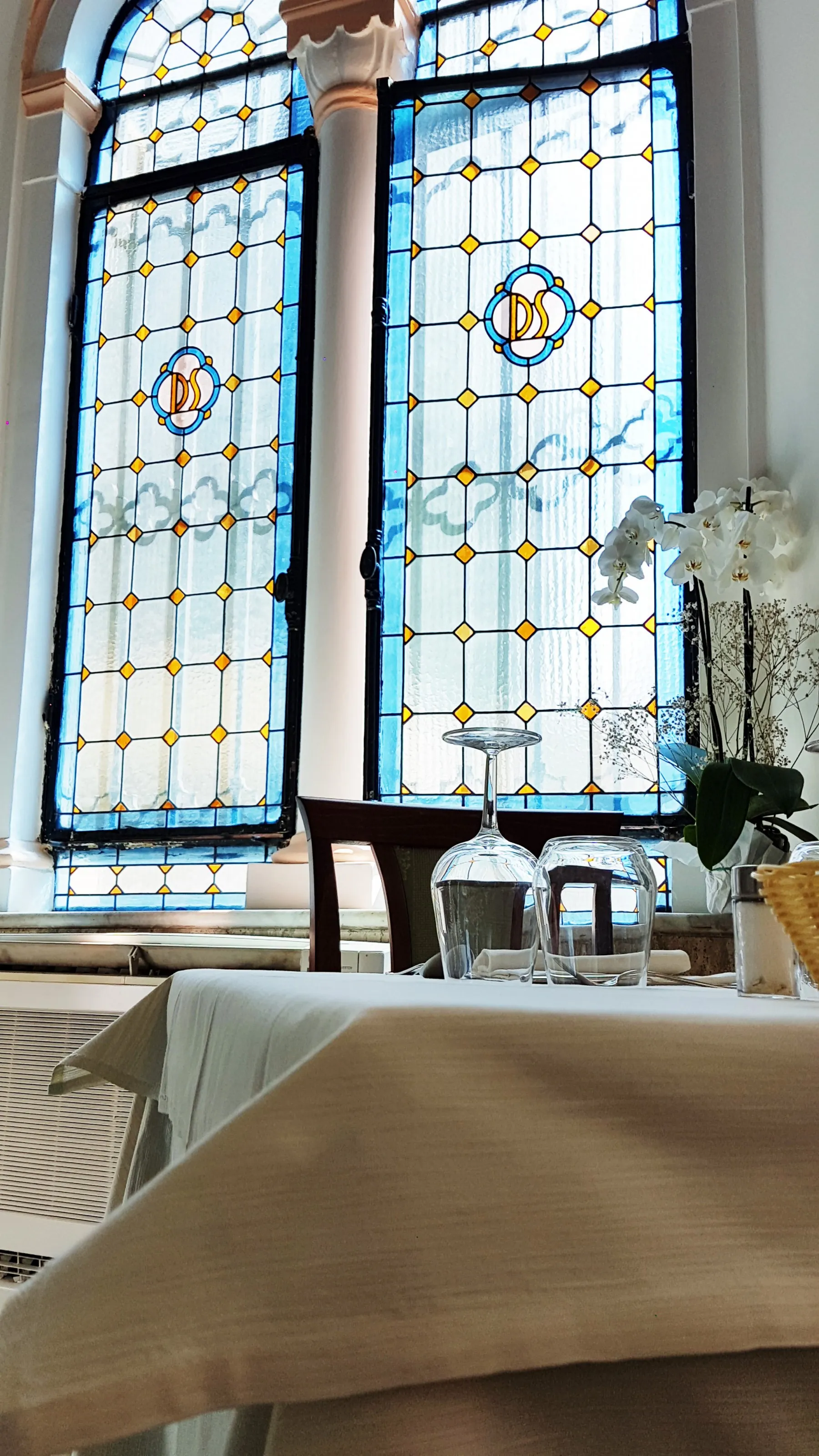 Sala ristorante con eleganti vetrate colorate in stile liberty e tavoli apparecchiati